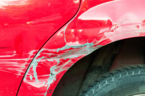 Red damaged car in car crash accident with scratched paint, dented.
