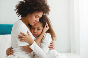 Child custody in divorce: Mother comforting her daughter, sitting in the bedroom, hugging