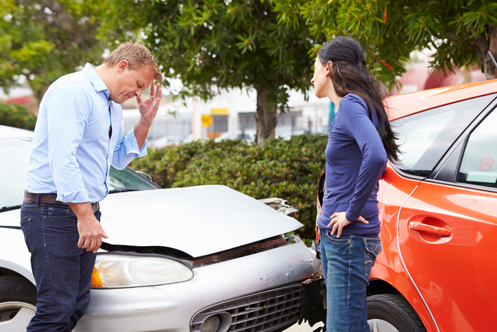 Two Drivers Arguing After Traffic Accident With Head In Hands.