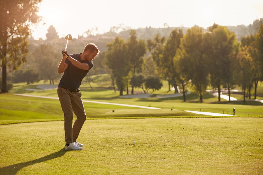 Male Golfer Lining Up Tee Shot On Golf Course