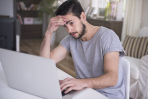 Personal Injury Lawyer Bergen County, NJ with a man holding his forehead looking stressed while looking at a computer